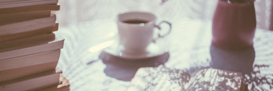 A close-up of a coffee cup and pile of books