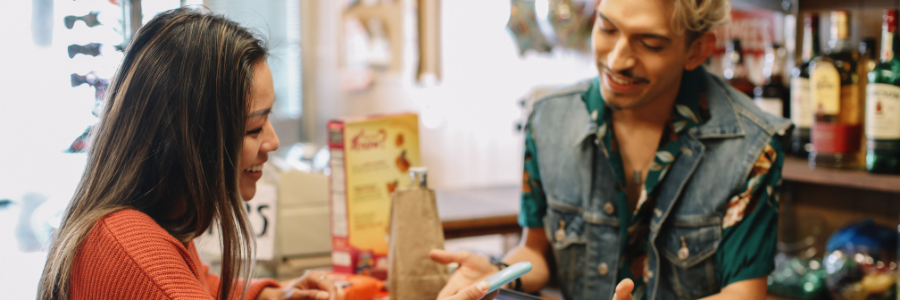 A person working in a convenience store serving a member of the public.