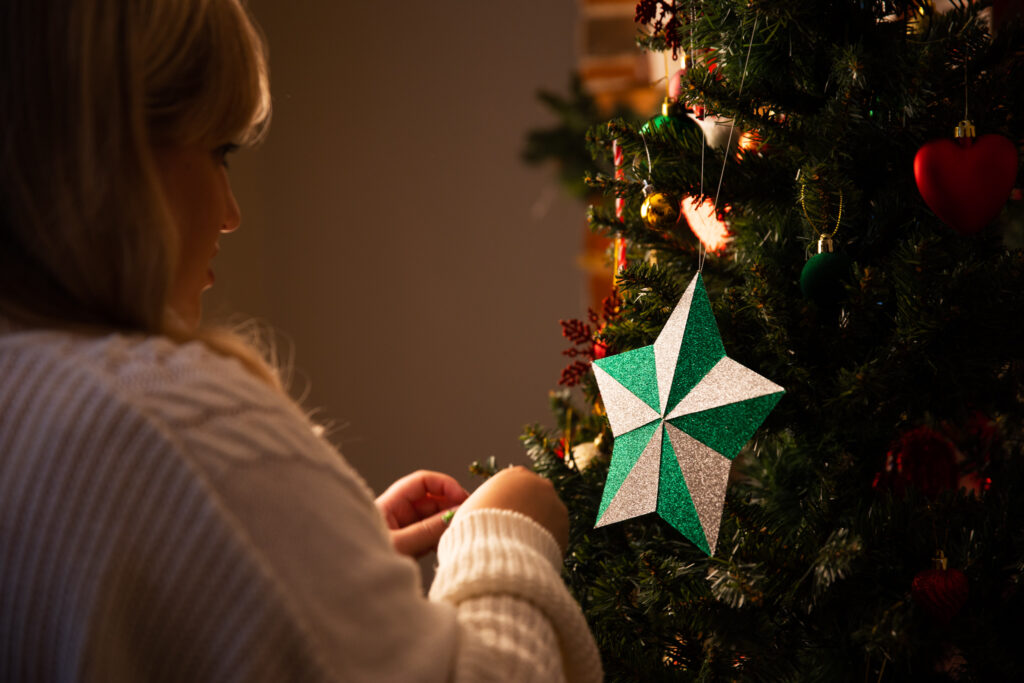 Woman hanging a green and white star on a Christmas tree
