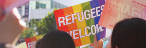 A person holding a sign that says 'Refugees Welcome'