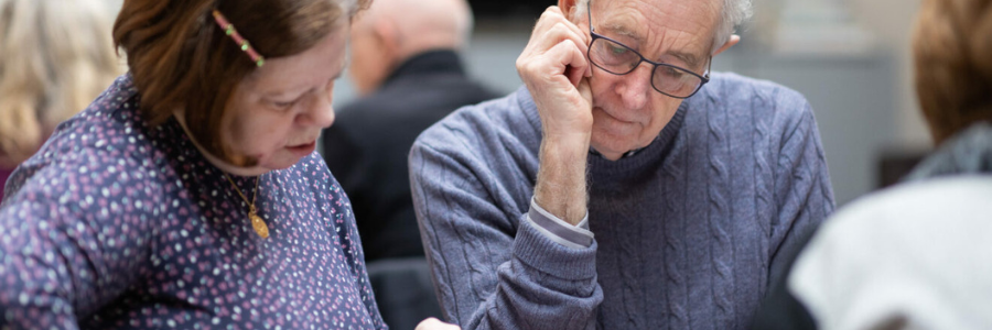 Close-up of two older people sitting together and looking intently at something.