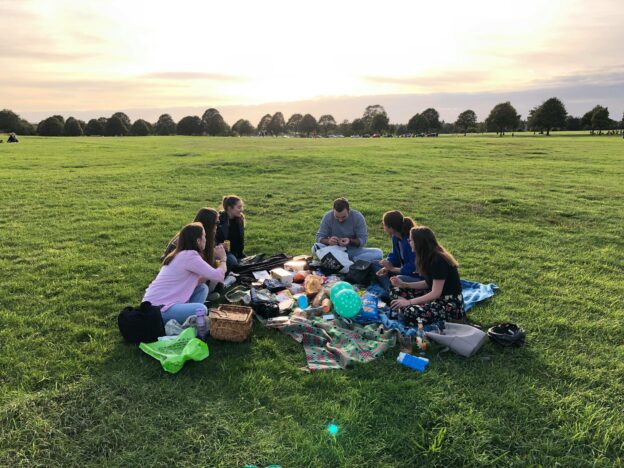 A group of 6 young people having in a large park