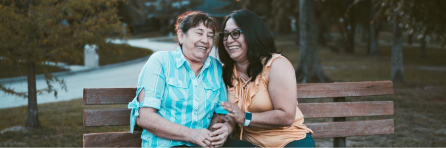 Two older people sitting on a bench.