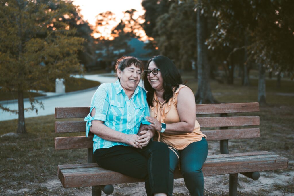 Two women laughing together on an outside bench