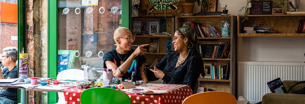 Two young people sitting together in a cafe, they are talking to each other and smiling