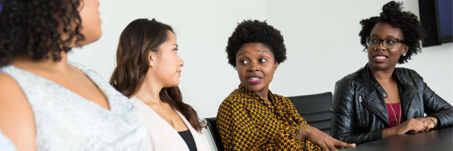 A group of four women talking to each other at a table.