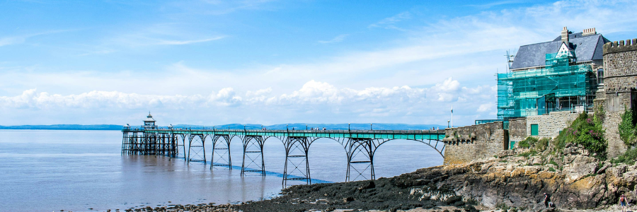 Photograph of Clevedon Pier during the daytime undergoing maintenance, wrapped in green netting.