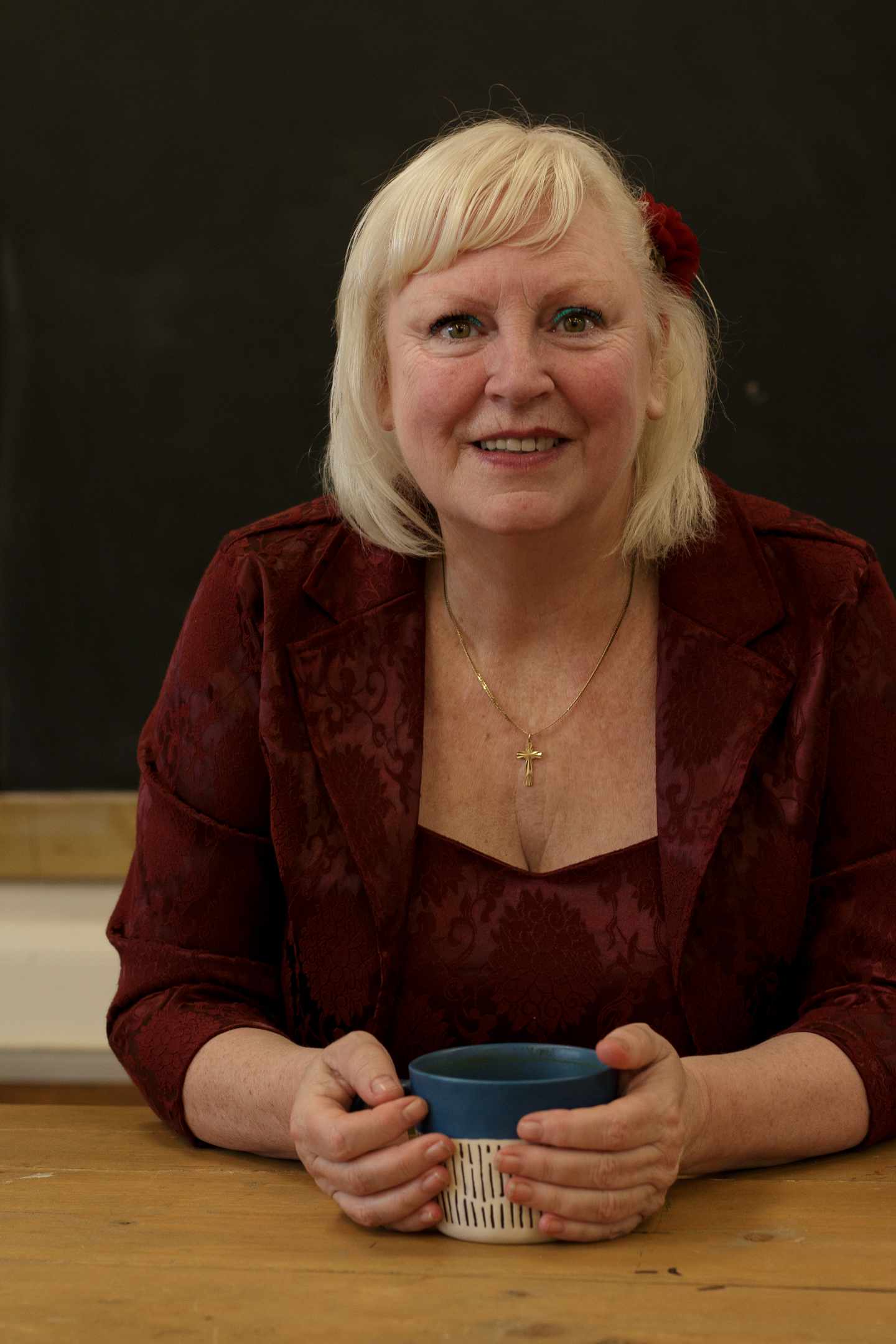 Headshot of the author sitting at a table holding a mug of coffee