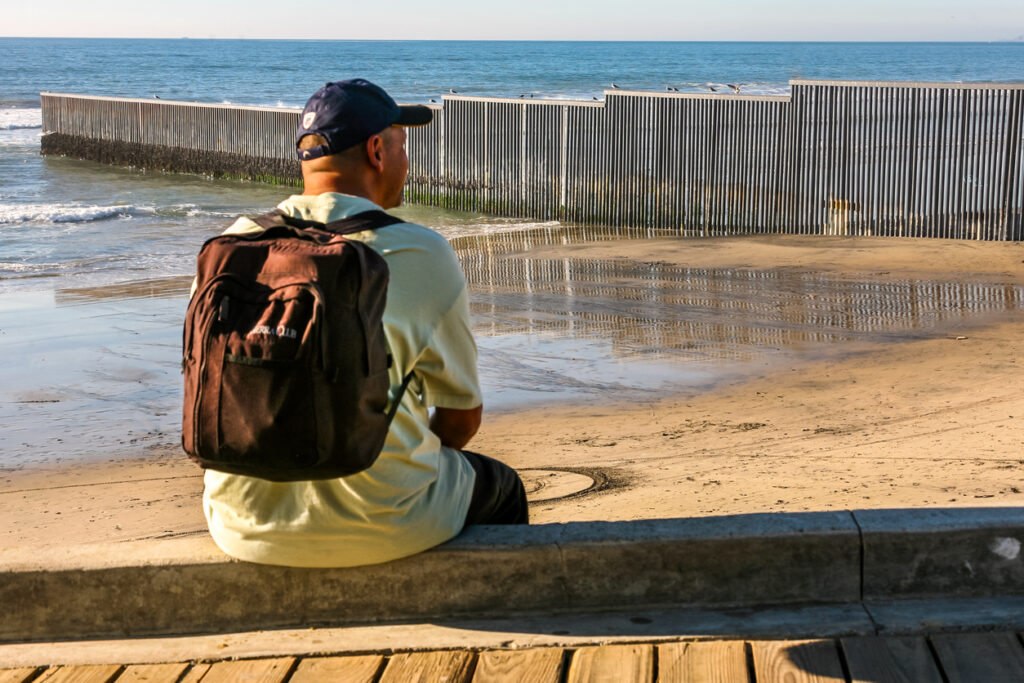 An adult man looks the steel wall along the US-Mexico border in Tijuana Beach in northern Mexico