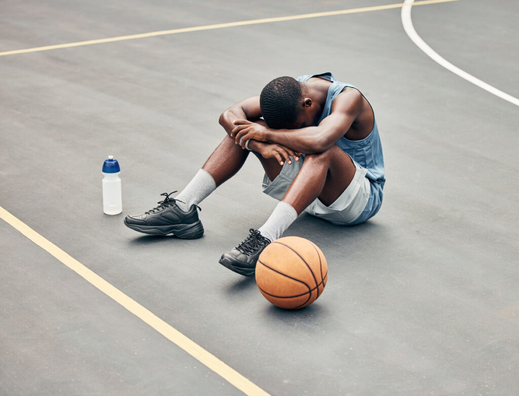 basketball player sat on court with his head down