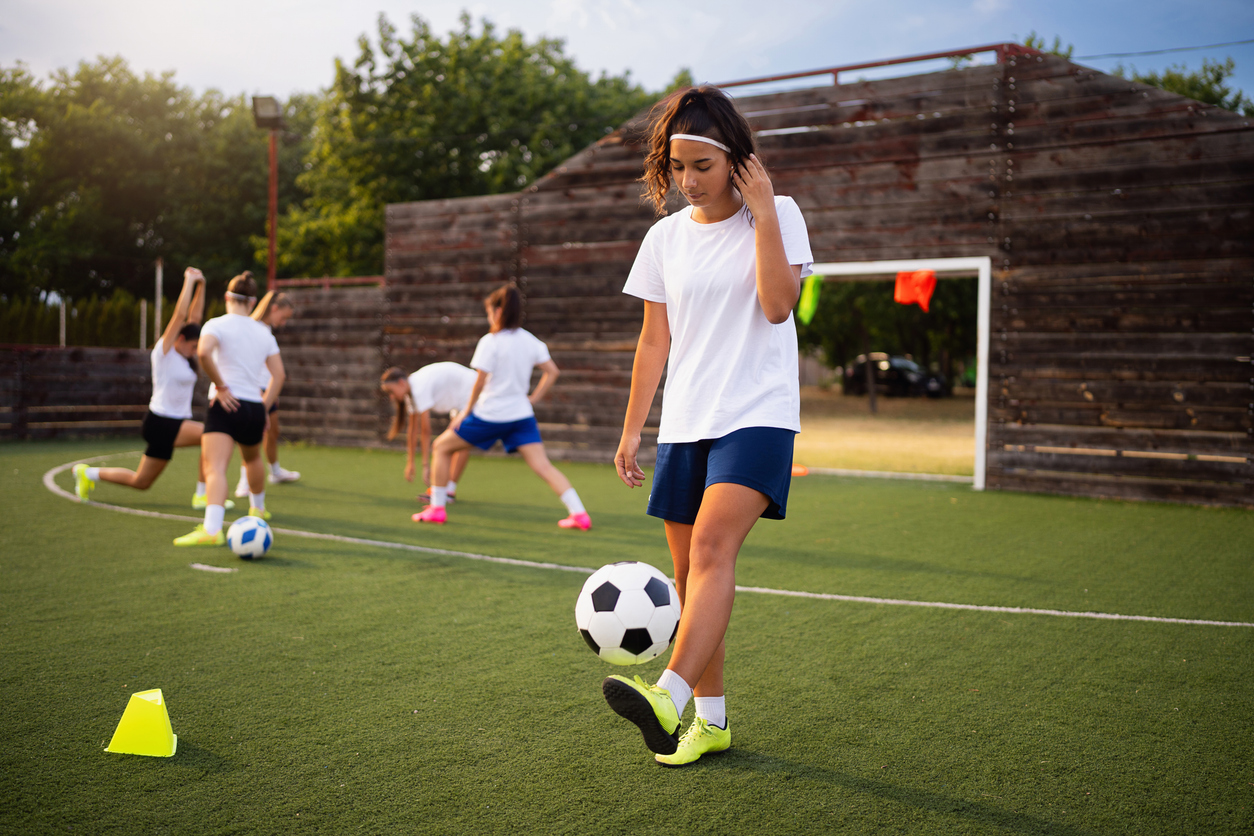 Caucasian teenage girl, a soccer player juggling the soccer ball during soccer practice