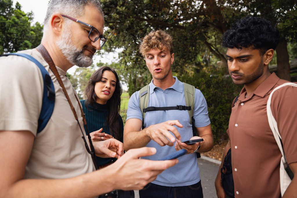 Group of Friends Exploring a Park Using Mobile Devices Together